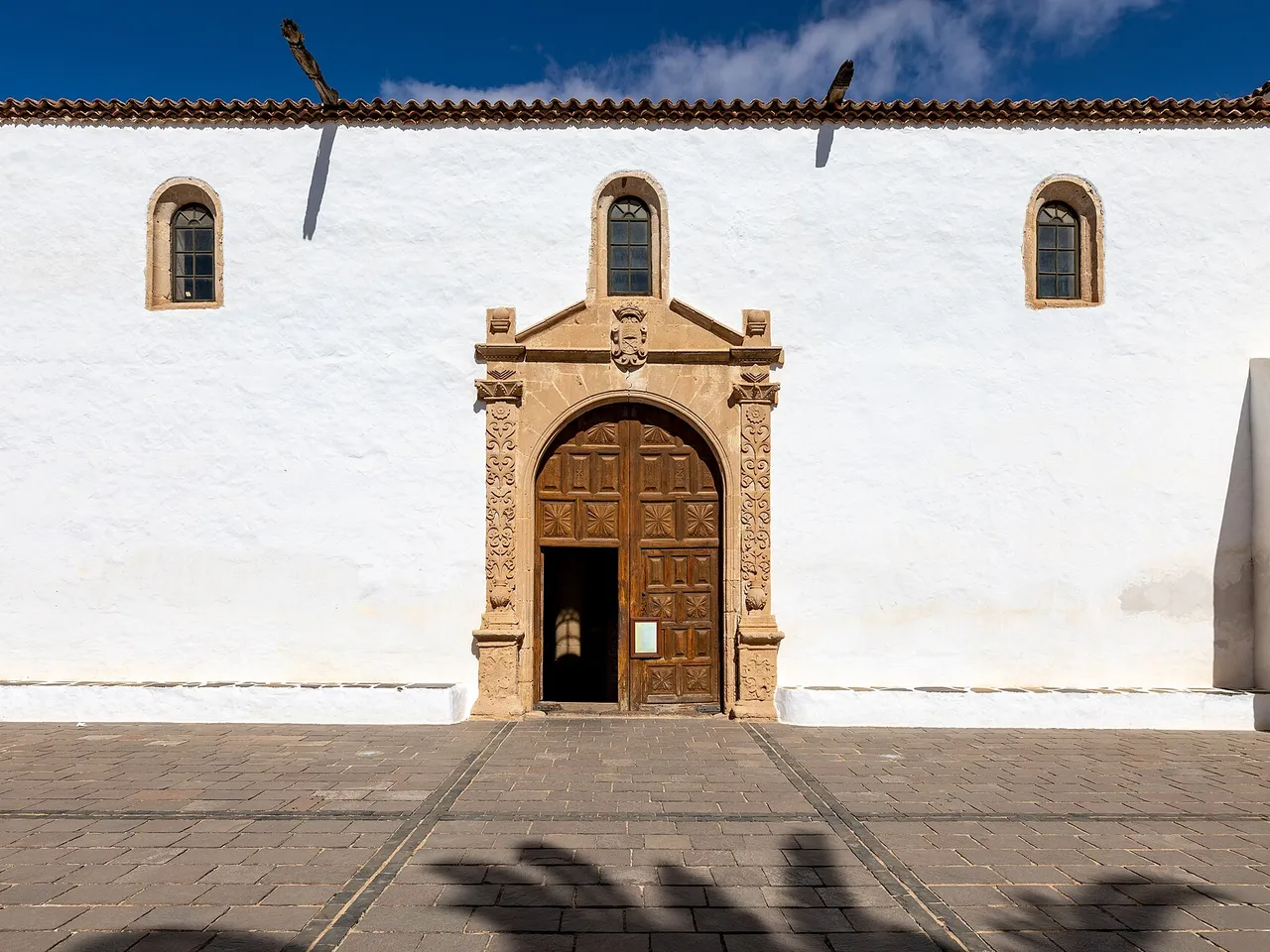 Fachada de la iglesia de Santa María de Betancuria en una plaza con palmeras