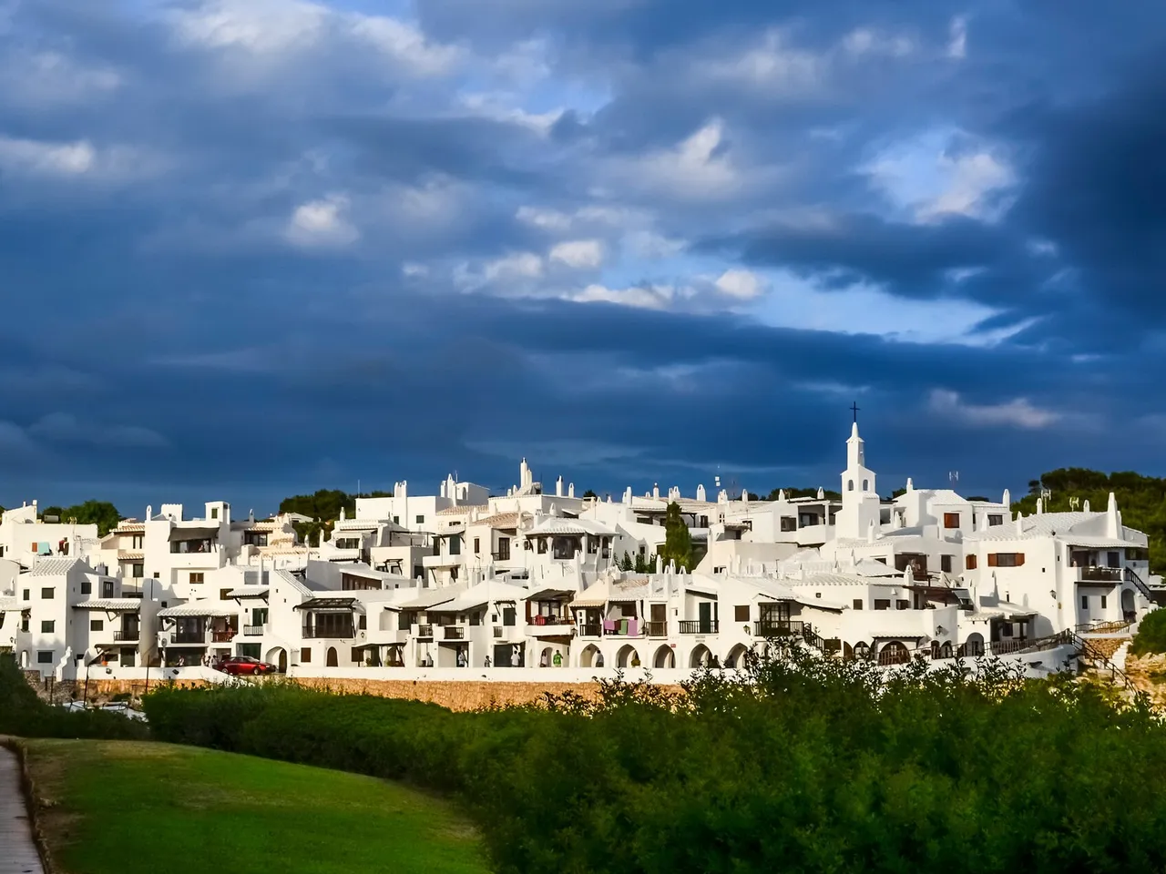 Panorámica de las casas blancas de Binibeca Vell bajo un cielo nublado