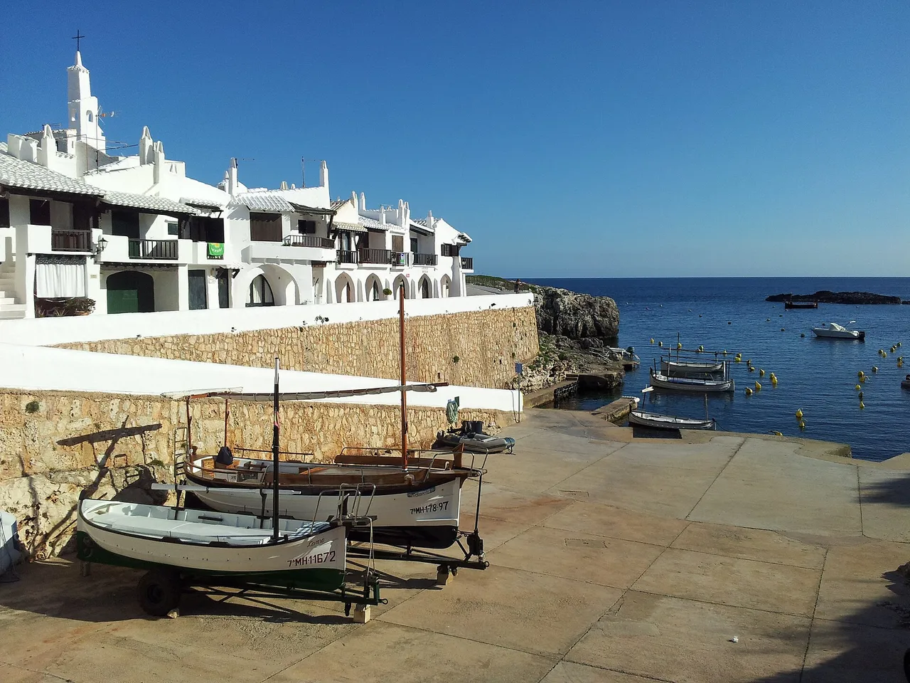 Casas blancas de Binibeca Vell con barcas en el muelle