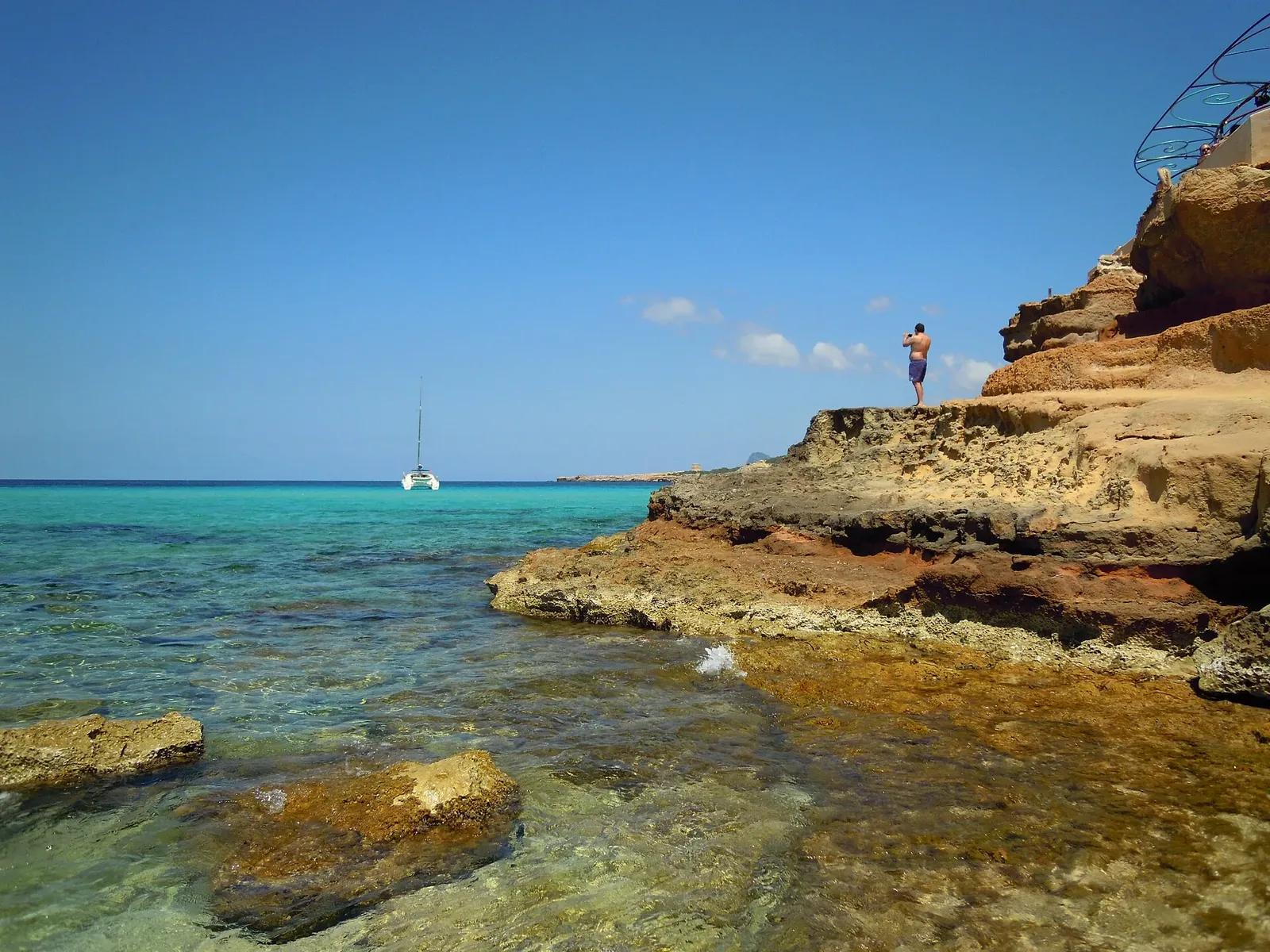 Rocas doradas y agua clara en las Platges de Comte