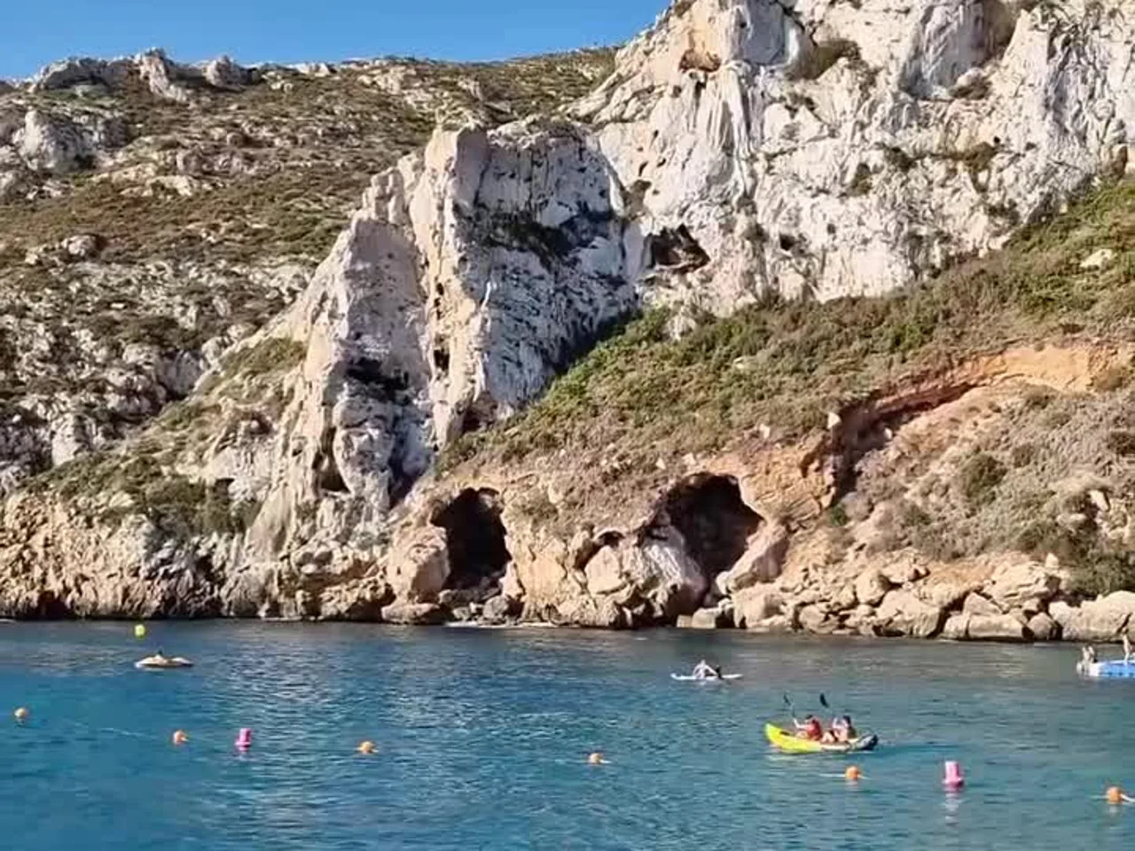 Cala Granadella con kayaks y bañistas bajo los acantilados