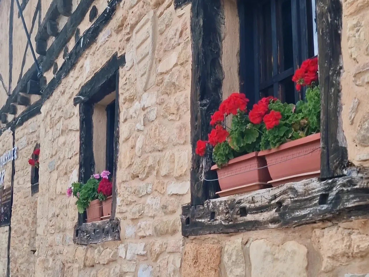Ventana con geranios rojos en una casa de piedra de Calatañazor