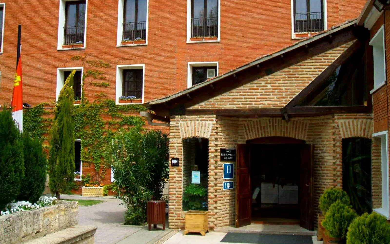 Entrada de la Hospedería San Zoilo con ladrillo y jardín en Carrión de los Condes