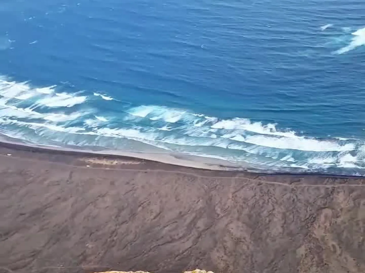 Olas rompiendo sobre la arena negra desde el Mirador del Río