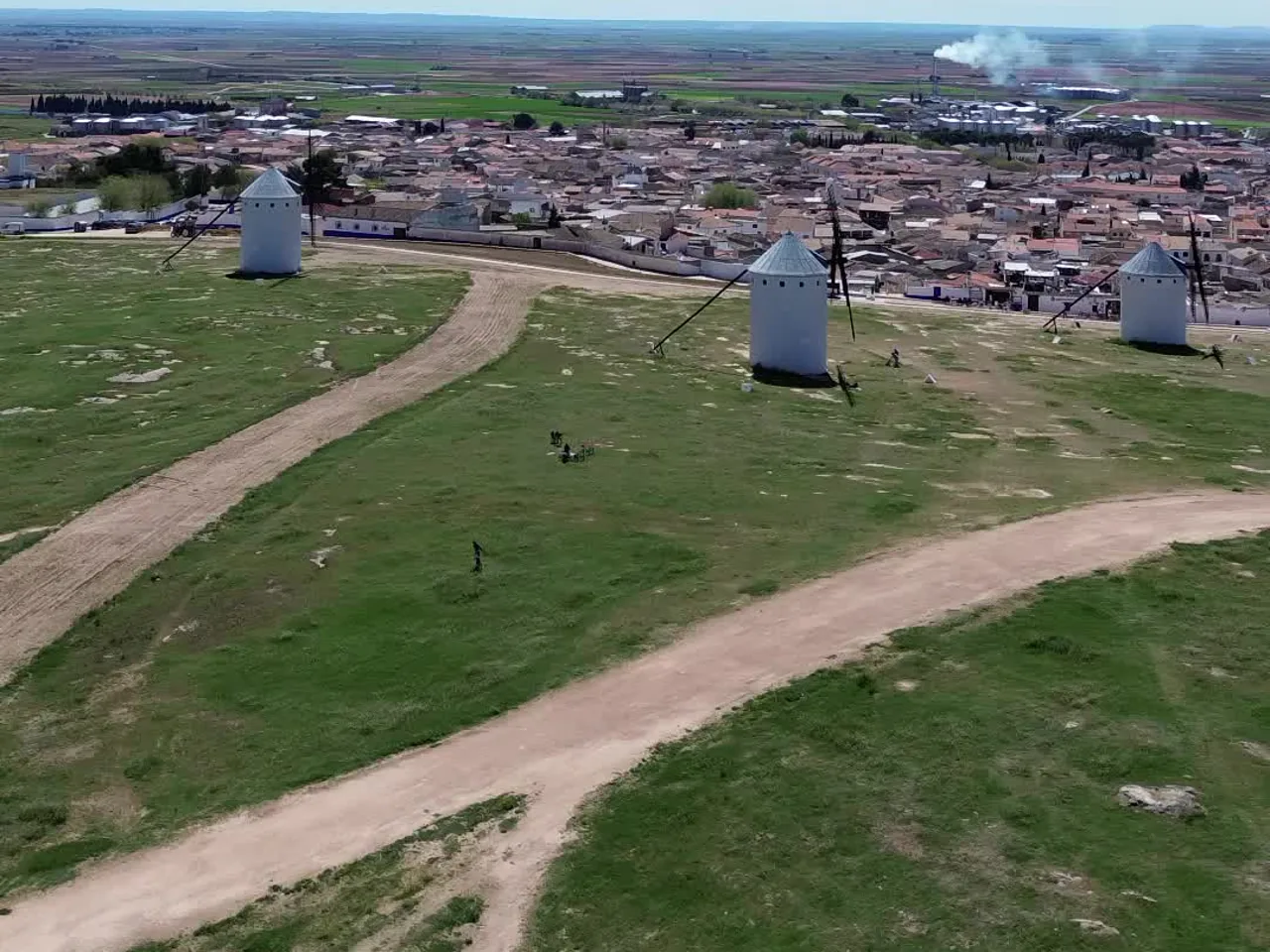 Molinos blancos con caminos entre la hierba en Campo de Criptana