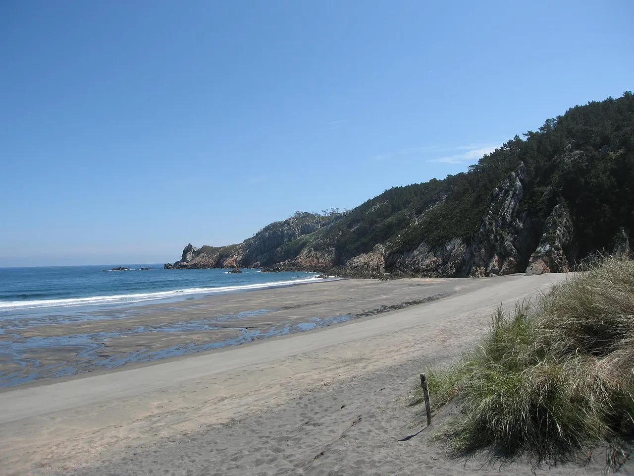 Arena y rocas con marea baja en Barayo