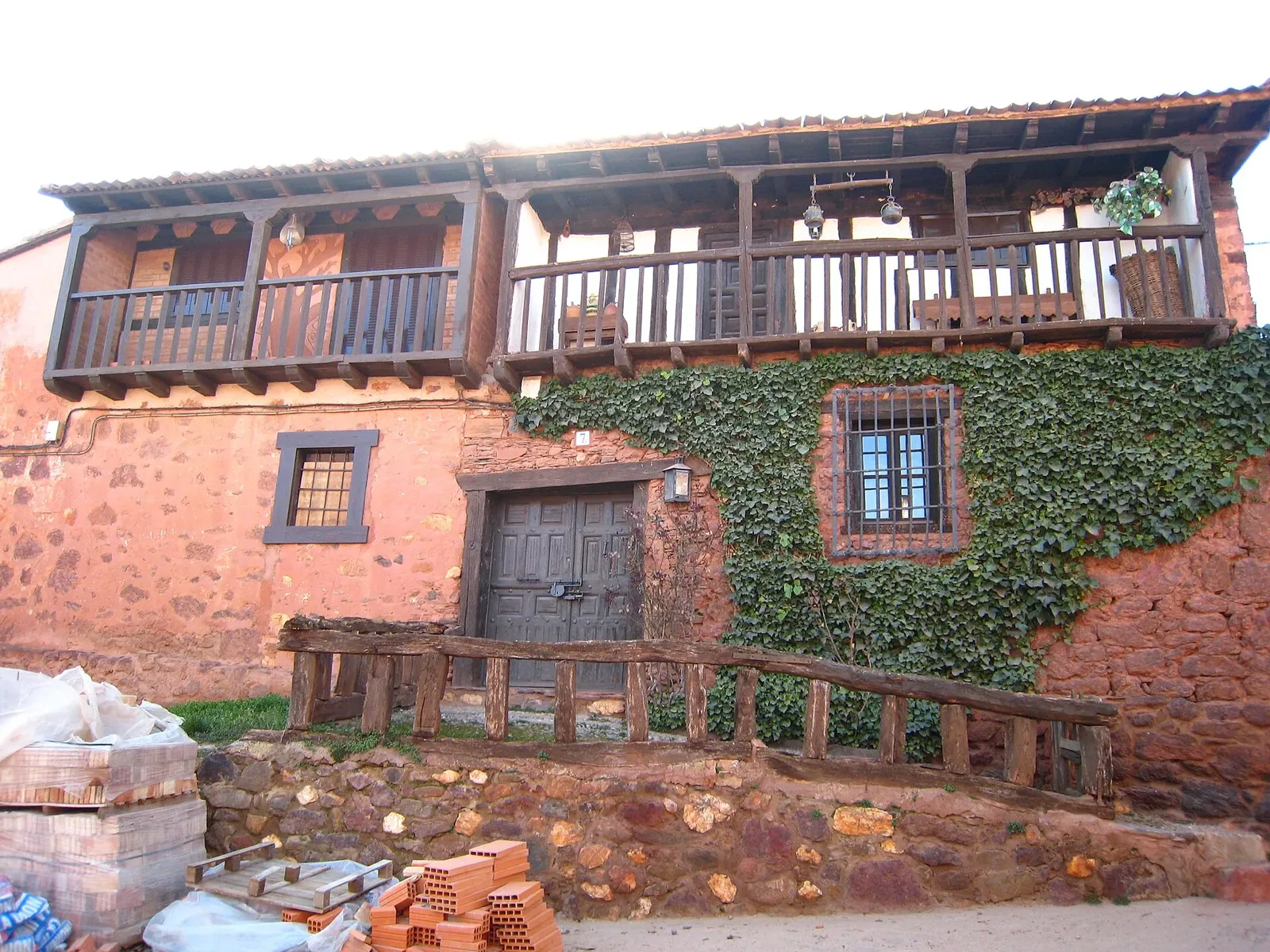 Casa roja con balcón de madera en Madriguera