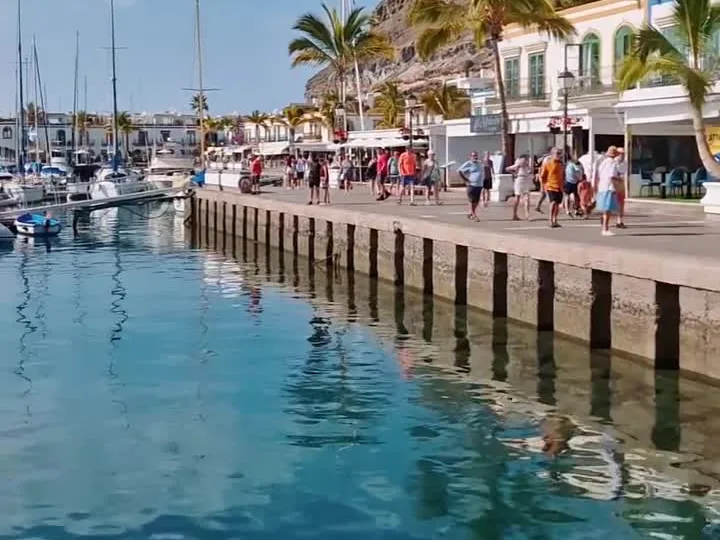 Muelle del puerto de Mogán con barcas y terrazas al fondo