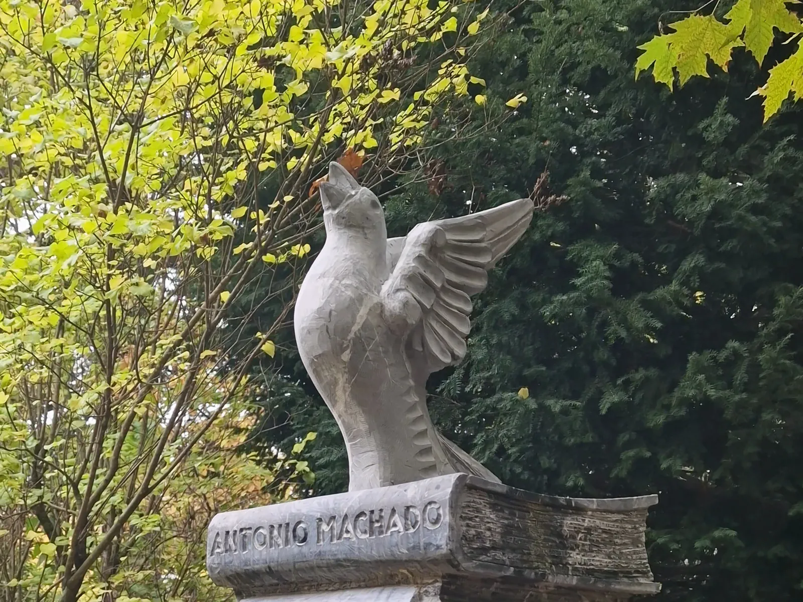Escultura de un pájaro sobre libros de piedra con el nombre de Antonio Machado en la Alameda de Cervantes
