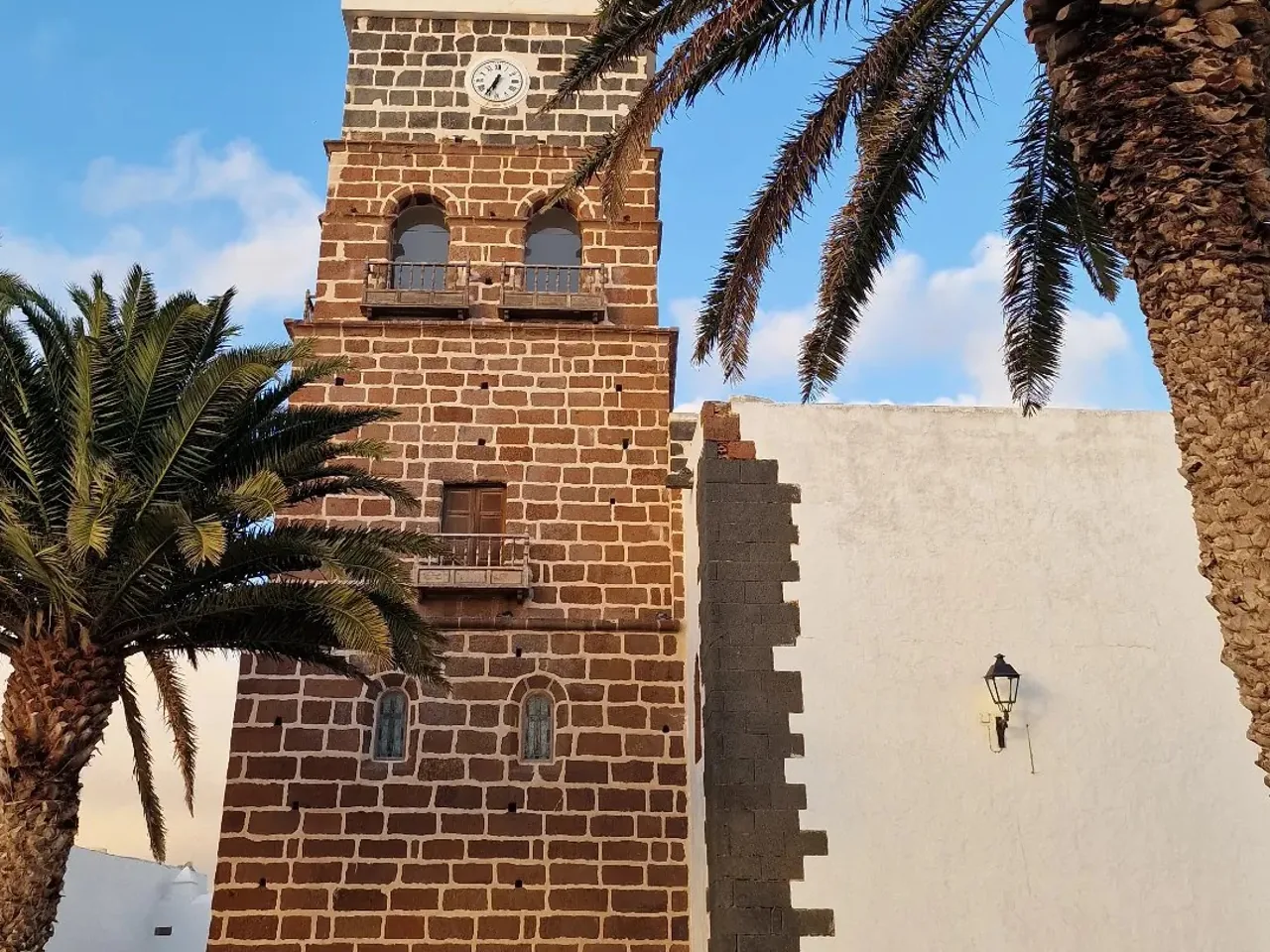 Torre de piedra de la iglesia de Teguise con palmeras